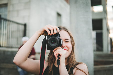 woman holding black Canon DSLR camera taking photo shallow focus photography thumbnail