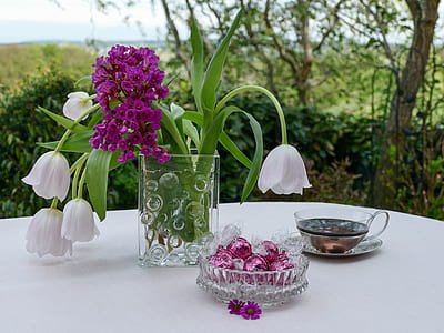 white and purple flower centerpiece near tea cup on white table thumbnail