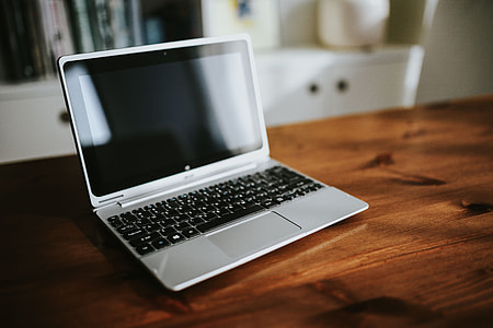 Silver laptop with various items on a table thumbnail