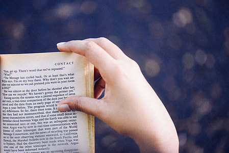 bokeh photography of person holding book thumbnail