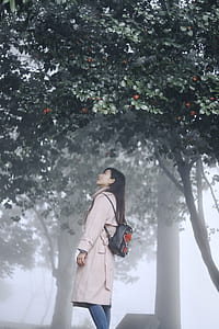woman wearing brown coat and black backpack under tree thumbnail
