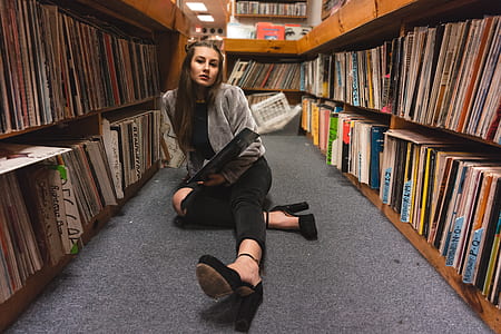 woman in gray open cardigan near on book lot thumbnail