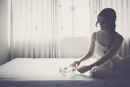 woman wears white spaghetti-strap dress sits on white mattress inside room thumbnail