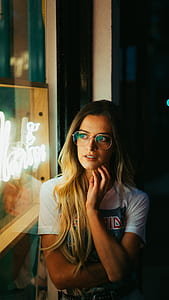 tilt-shift photography of woman standing beside LED light signage thumbnail