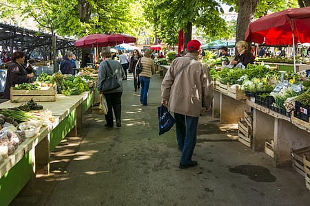 people walking on pathway in between vegetable stands thumbnail
