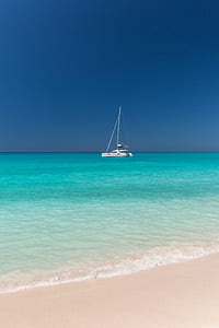 yacht parked on beach with white sand under blue sky thumbnail