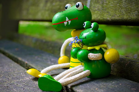 two green frog and crocodile toys sitting on brown bech thumbnail