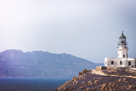 white lighthouse on hilltop in front of body of water thumbnail