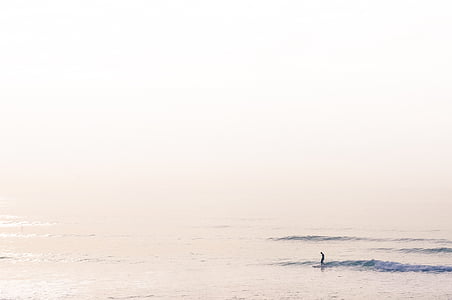 person standing on body of water under white clouds thumbnail