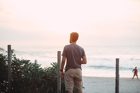 man wearing gray shirt standing on beach shore thumbnail