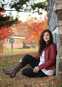 smiling woman wearing red jacket and white shirt sitting on ground thumbnail