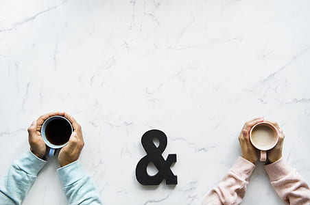 two person holding white and blue ceramic mugs with liquid thumbnail