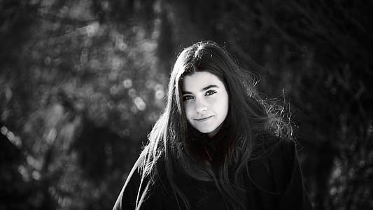 Grayscale Photo of Woman Wearing Coat Surrounded With Trees thumbnail