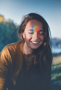 smiling woman in brown shirt with eyes closed thumbnail