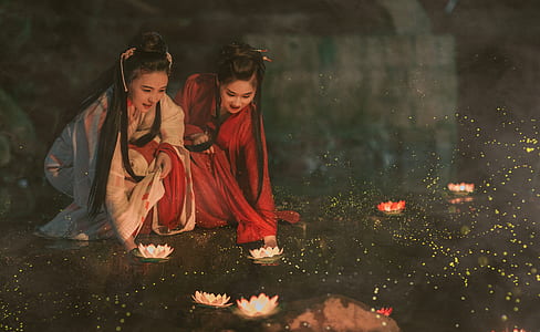 two women beside the river with lotus candles thumbnail