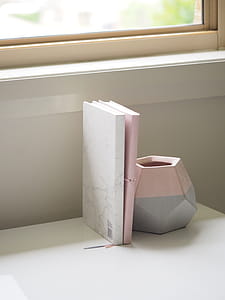 White and Pink Books Piled Beside Pink and Gray Ceramic Vase thumbnail