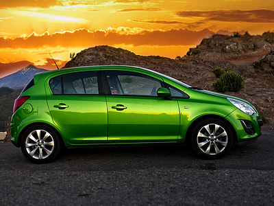 green 5-door hatchback on gray asphalted road across brown mountain during golden hour thumbnail
