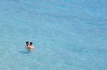 aerial view photography of couple swimming during daytime thumbnail