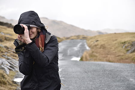 woman in black hooded jacket and black DSLR camera thumbnail