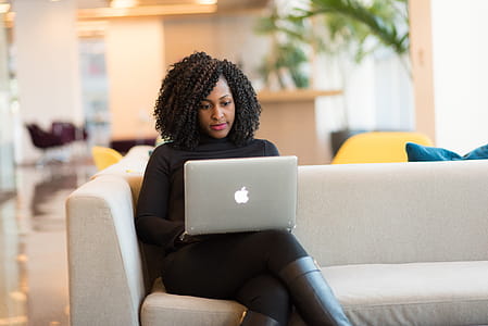 Woman Using Macbook Sitting on White Couch thumbnail