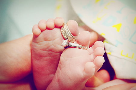 baby's feet with two silver-colored rings thumbnail