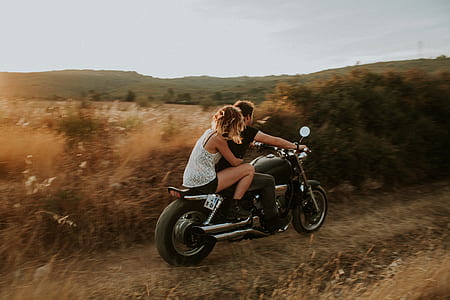 woman hugging man driving motorcycle near plants thumbnail