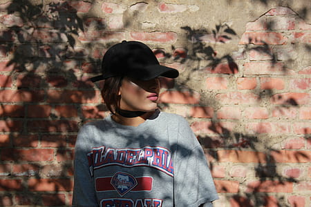 woman wearing gray crew-neck t-shirt standing on brown wall brick thumbnail
