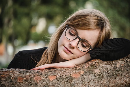 woman holding brown branch while sleeping surrounded by green leafed trees outdoors thumbnail