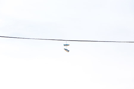pair of blue sneakers hanging on cable thumbnail