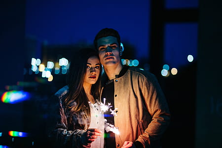 man and woman holding sparklers during nighttime thumbnail