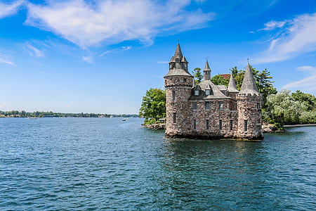 brown castle surrounded with body of water under cloudy sky thumbnail