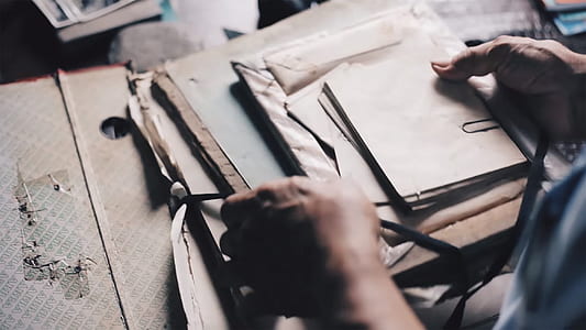 person holding white and brown papers thumbnail