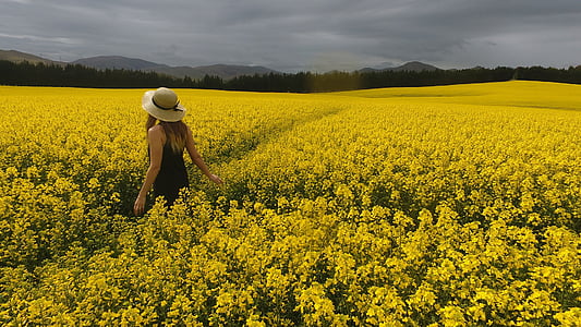 photo of woman wearing brown sleeveless dress near yellow flowers thumbnail
