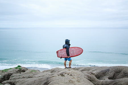 man holding surfboard on rock thumbnail