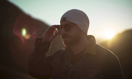 man wearing white knit hat holding sunglasses thumbnail