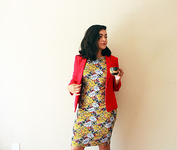 woman holding cup while standing near wall thumbnail