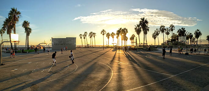 panorama shot of people playing basketball during golden hour thumbnail