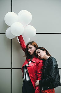 woman wearing red leather jacket holding white balloons near wall thumbnail