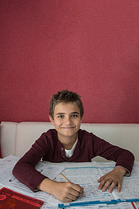 boy sitting on sofa in front of table while smiling and holding pen thumbnail