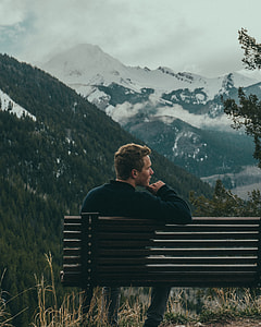 image contains man sitting on bench near mountains thumbnail