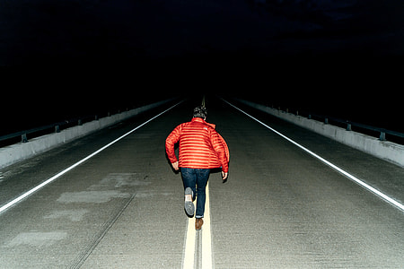 person running on gray road at nighttime thumbnail