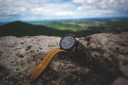 round black and brown analog watch on brown rock thumbnail