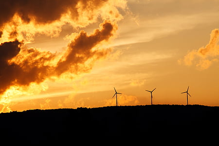 silhouette photograph of wind turbines during golden hour thumbnail