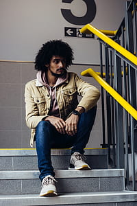 man sitting on concrete stairs beside handrails thumbnail