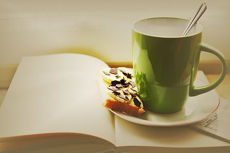 green and white ceramic mug place on saucer and book thumbnail