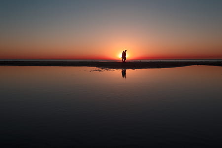 man standing on beach sand during golden hour thumbnail