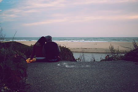 couple sitting in front of beach during daytime thumbnail