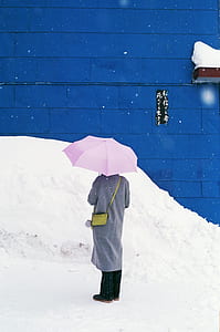 person wearing gray cardigan and black pants holding pink umbrella thumbnail