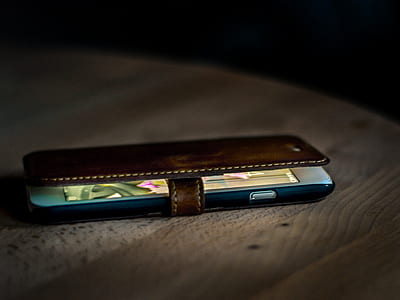 post-2016 iPhone covered with brown leather flip case on top of brown wooden surface thumbnail