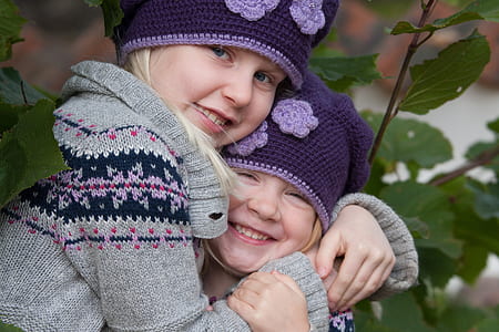 girls in grey and black sweaters while hugging each other thumbnail